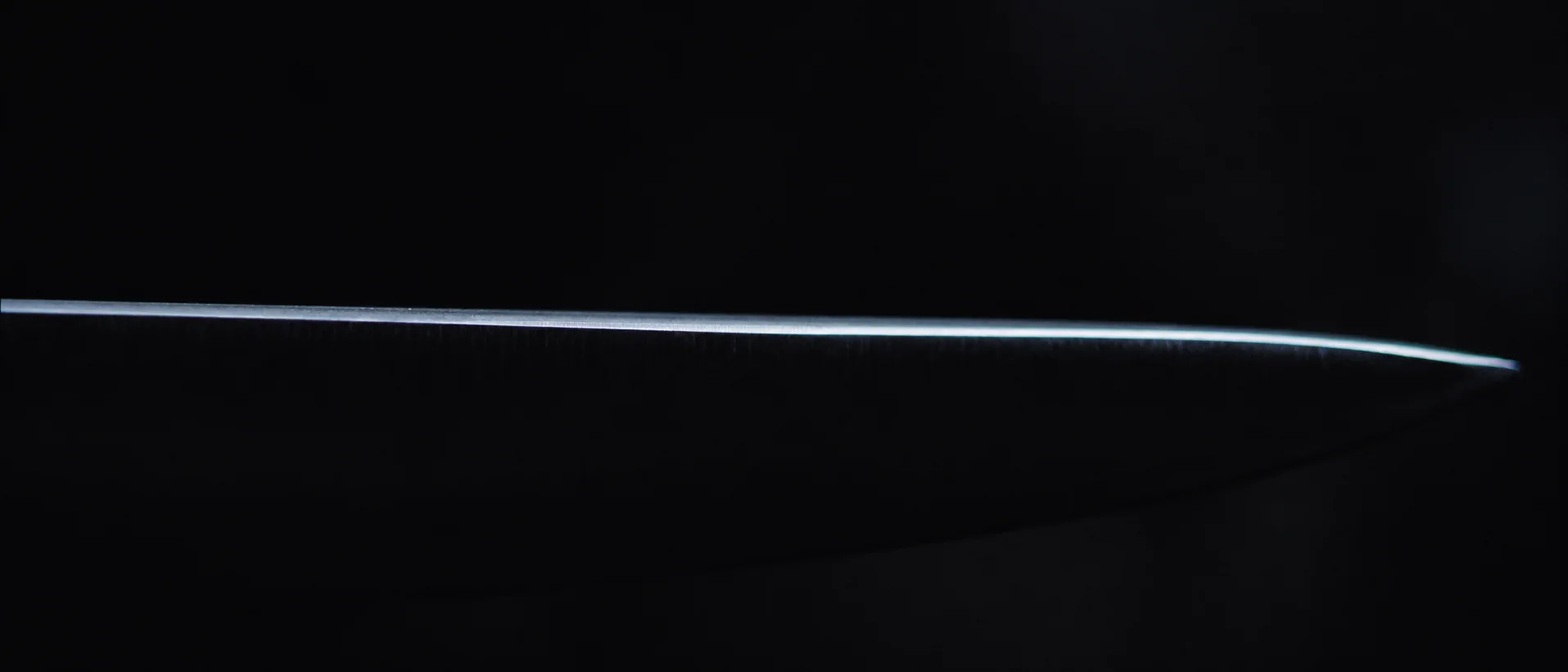 Le fil d’une lame de couteau accroche un trait de lumière dans l’obscurité